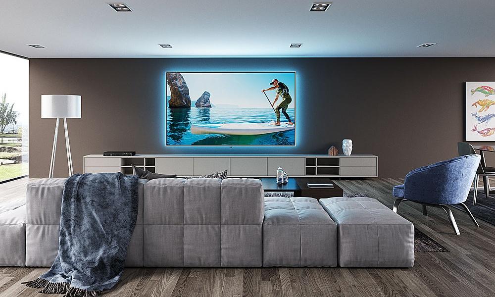 Contemporary media room with wall-mounted TV, blue accent lighting, and modular sofa