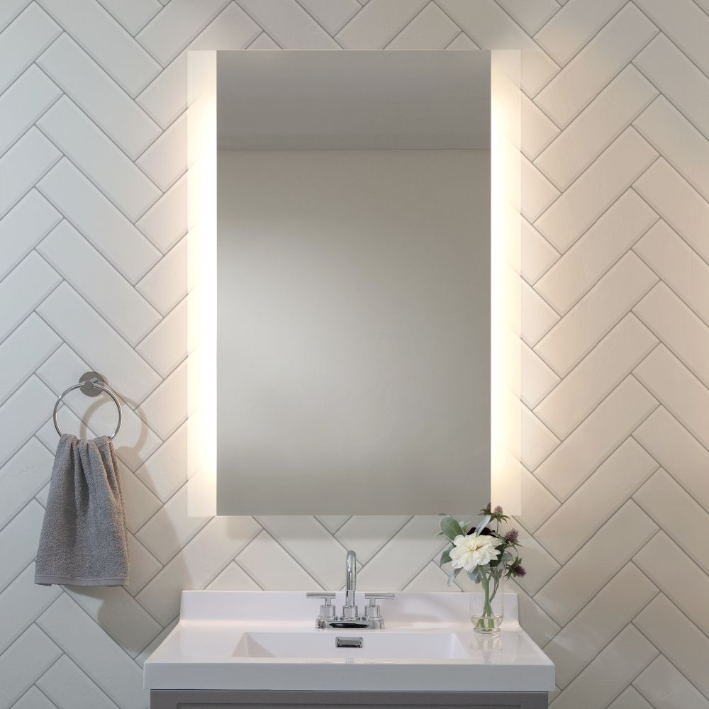 Round backlit mirror above a vanity with warm ambient lighting