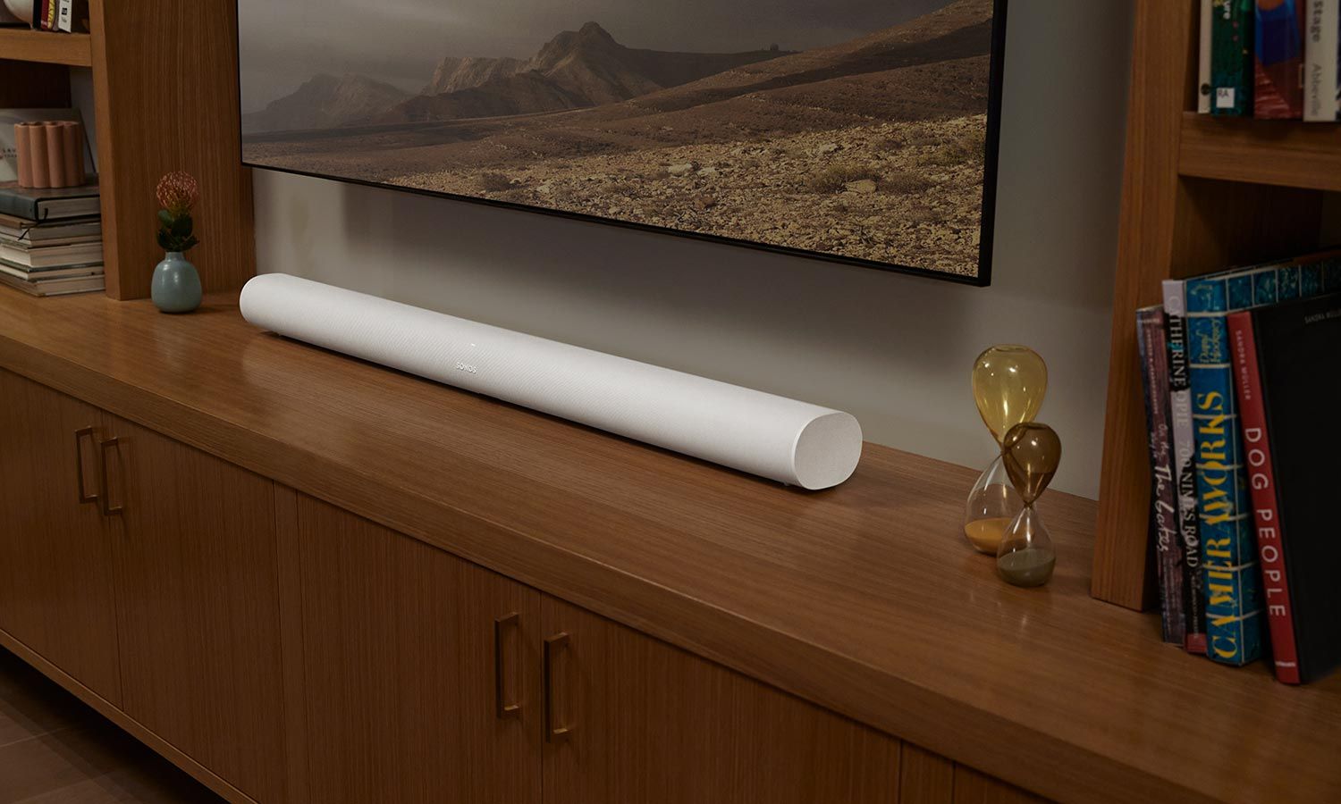 Sonos soundbar placed on a wooden cabinet beneath a mounted TV, delivering high-quality audio.