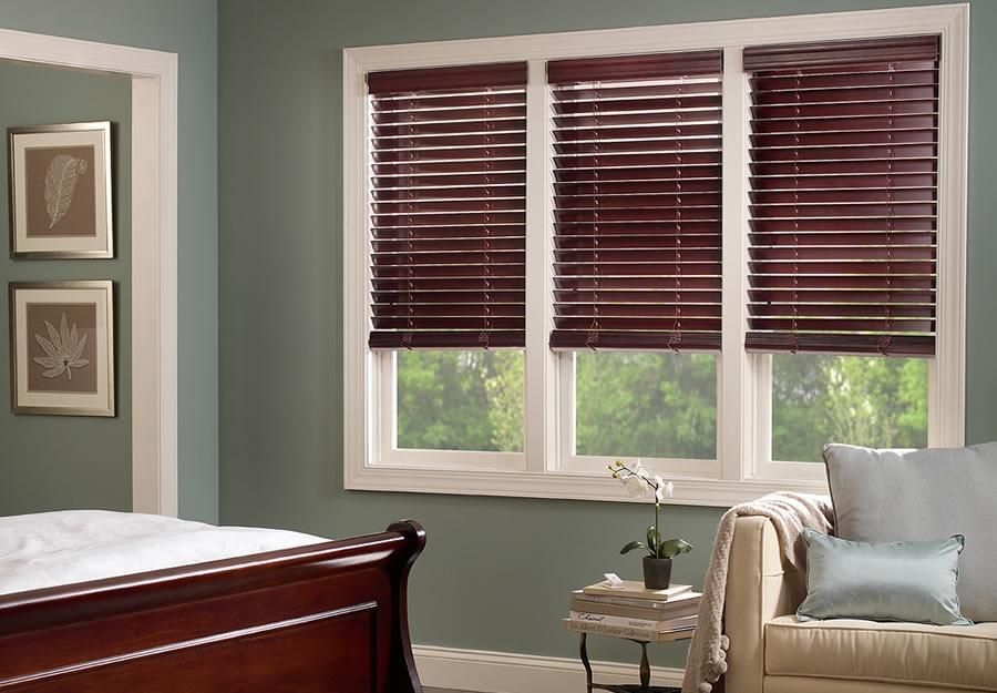 Lutron wood blinds in a bedroom with classic decor, featuring dark wood furniture and light-colored walls.