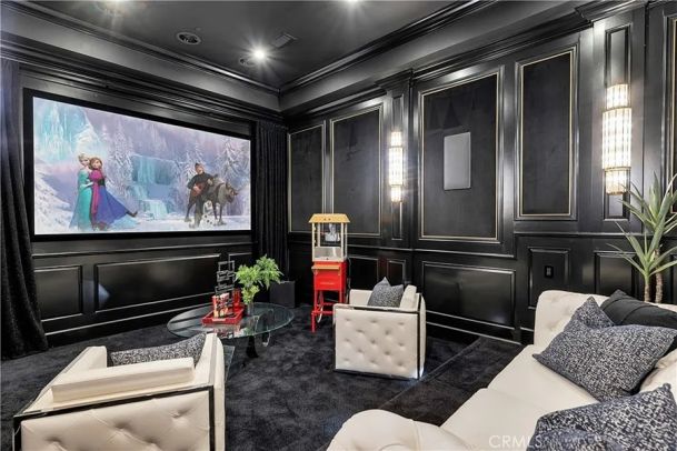 Dedicated home theater in residential home featuring a projector, screen, acoustics and custom seating