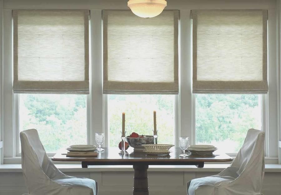 Lutron Roman shades in a dining area with multiple windows, creating a soft, elegant look.